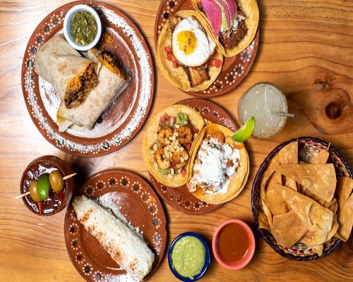 A traditional Mexican meal setup with beans, tortillas, and fresh vegetables
